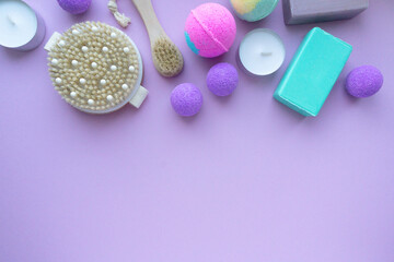 Set of spa products. Bath bombs, soap and massage brushes on purple background, space for text