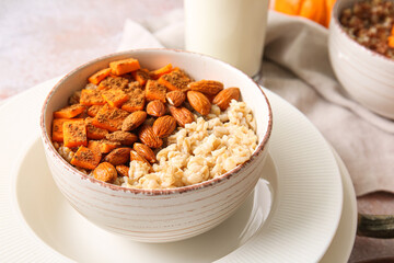 Bowl of tasty oatmeal with pumpkin and almond on light background