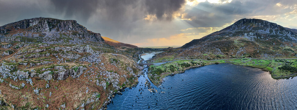 Aerial panoramic view of the stone Wishing Bridge over winding stream in green valley at Gap of Dunloe in Black Valley of Ring of Kerry, County Kerry, Ireland