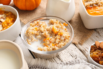Bowl of tasty oatmeal with pumpkin on white wooden background