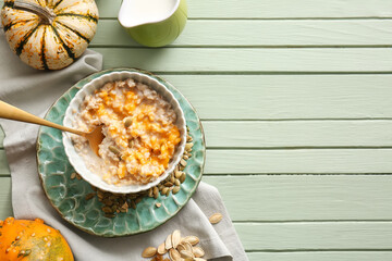 Bowl of tasty oatmeal with pumpkin on green wooden background