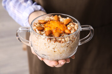 Woman holding pot of tasty oatmeal with pumpkin, closeup