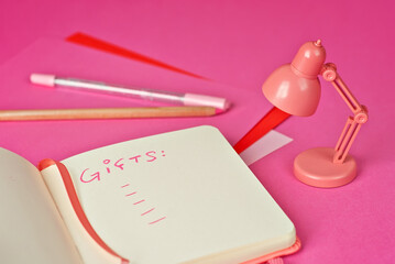 Notebook on a pink background. Toy table lamp near the notebook. Copy space and free space for text in notebook. Mockup for design. The word 