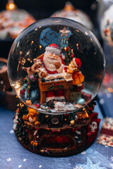 Magic crystal ball with a toy Santa Claus. New Year's souvenir and Christmas gift. Festive magic details. Vertical postcard