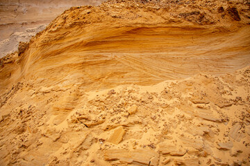 Textural sand, with  relief surface, multi-colored layers and different in size of granules, in outdoor sand career, after mining ore and sand for construction.