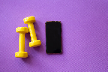 Yellow dumbbells on a lilac sports rug