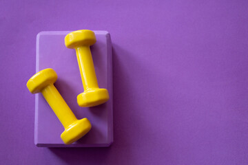 Yellow dumbbells on a lilac sports rug