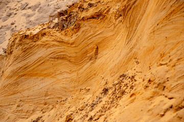 Textural sand, with  relief surface, multi-colored layers and different in size of granules, in outdoor sand career, after mining ore and sand for construction.