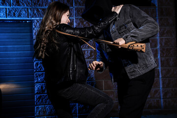 Woman fighting with thief while he trying to steal her bag near car at night. Self defense concept