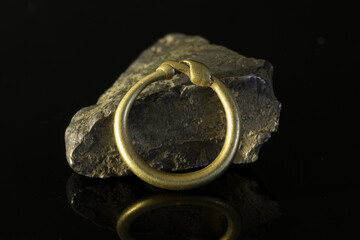Small viking gold ring leaning towards bar of silver