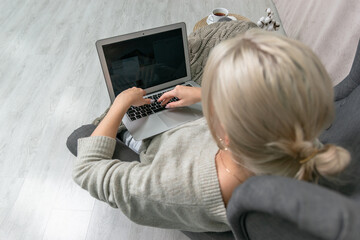 Young girl with a laptop under a blanket in a chair