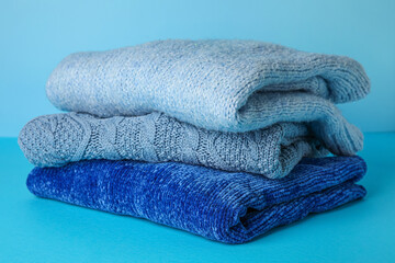 Warm knitted sweaters on color background