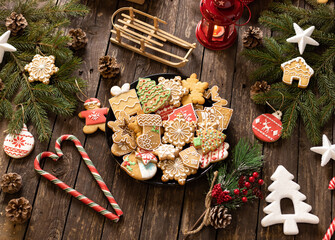 Cookies, candy and biscuits in festive winter holiday shapes nicely arranged on a plate placed on a wooden table with Christmas decoration and ornaments, winter holidays