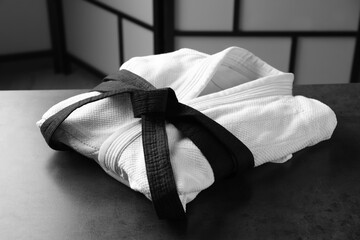 Martial arts uniform with black belt on grey stone table indoors © New Africa