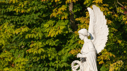 Statue of ancient beautiful winged angel in downtown city park of Potsdam in Summer at sunset,...