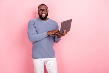 Photo of cute cheerful afro guy wear pullover glasses typing modern device empty space isolated pink color background