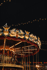 Shiny golden children's magic carousel with horses Merry-go-roundi n the evening lights. Vertical