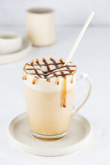 Caramel latte macchiato with coconut milk in a glass mug.