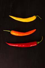 Fresh peppersyellow, orange and red colors on black wooden background. Copy space. Flat lay.