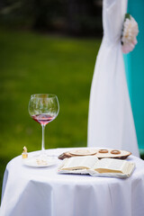 Bible, vine and wedding rings on a table in a garden. Reading outdoor. Relax on air. Poetic. Wedding ceremony outdoor. Wedding ceremony decoration in the garden.