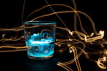 A vessel, a glass filled with a transparent liquid with an electric lightning and beating from the surface. On a black background