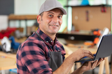 shot of a smiling carpenter using laptop at work