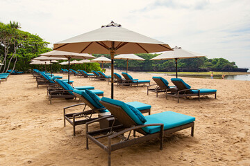 Sun beds and umbrellas on the white sandy beach of Nusa Dua, Bali, Indonesia