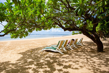 Sun beds and umbrellas on the white sandy beach of Nusa Dua, Bali, Indonesia