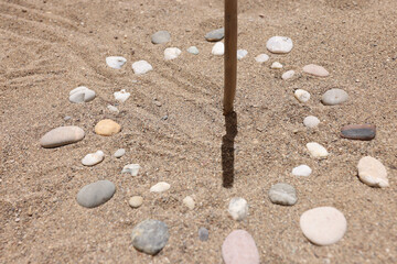 Sundial made of stones on sand closeup background - obrazy, fototapety, plakaty
