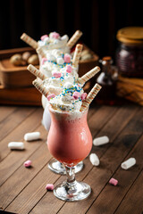 Side view on four glasses of sweet milkshakes with biscuits