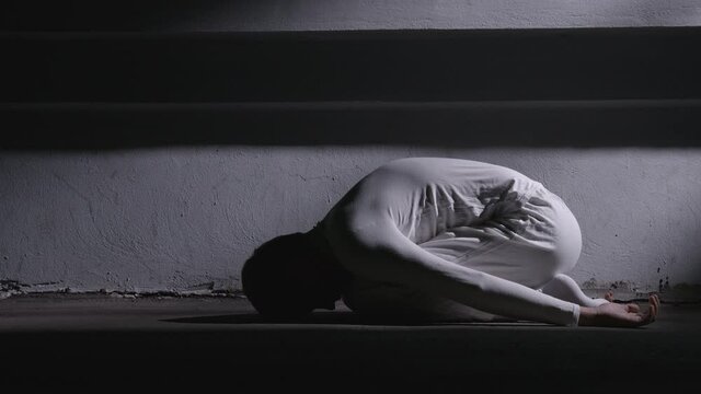Shooting of mad man in white clothes lying in fetal position