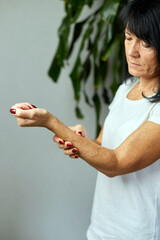 Mature woman massaging wrist, feeling pain in joint