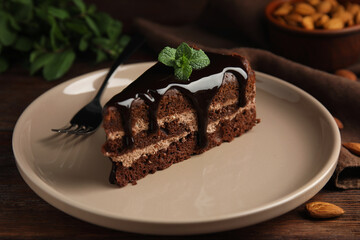 Piece of tasty homemade chocolate cake with mint on wooden table, closeup