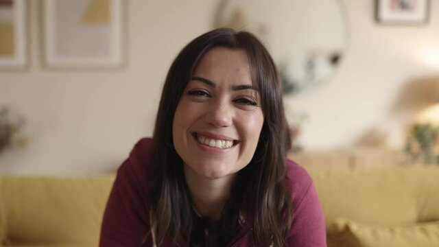 Portrait of happy carefree hispanic young woman smiling and looking at camera webcam making video call while sitting at home. High quality 4k footage