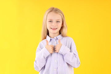 Cute little girl in shirt on yellow background