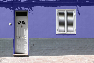 Weiße Holzhaustür und weißes Fenster an der Wand mit grauem Backstein. Farbtrend des Jahres.