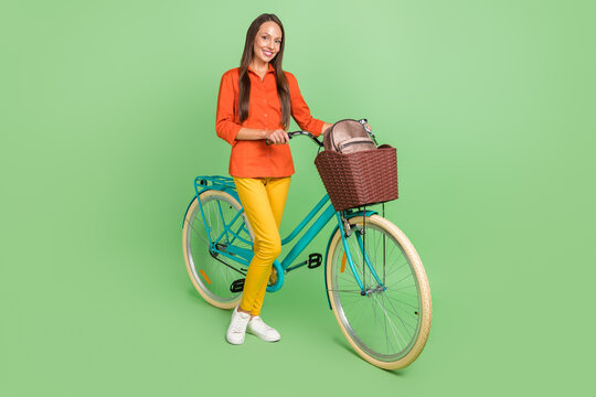 Full size photo of cheerful mature woman spend free time riding bicycle isolated over green color background