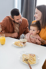 Obraz na płótnie Canvas Positive parents sitting near son and tasty dinner at home