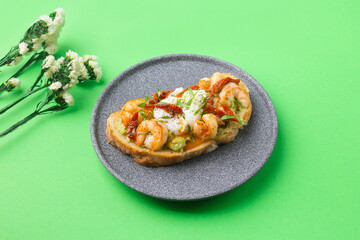 Toast with shrimp, prawns, avocado and poached egg on green background with flowers