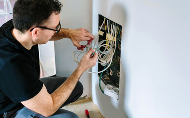 Male technician cutting cable to install telecommunication box