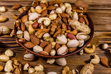 Various nuts (almond, cashew, hazelnut, pistachio, walnut) in ceramic plate on a wooden table. Vegetarian meal. Healthy eating concept
