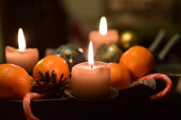 Three burning candles with manadarins and a pine cone as christmas decoration