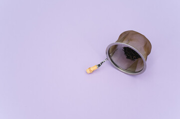 worn metal tea strainer on a lilac paper background