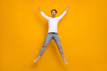 Fototapeta na wymiar Full body photo of great brunet young guy jump wear shirt jeans shoes isolated on yellow background