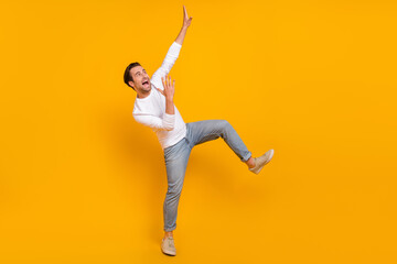 Full length photo of cool brunet young guy dance look promo wear shirt jeans sneakers isolated on yellow background