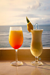 Two cocktails Pina Colada and Tequila Sunrise on the beach bar with sea view at sunset, Bali, Indonesia