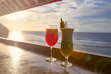 Two cocktails Pina Colada and Tequila Sunrise on the beach bar with sea view at sunset, Bali, Indonesia