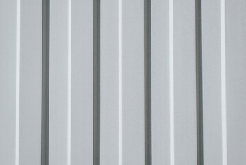 Iron, gray construction profiled sheet with vertical stripes. Closeup of a corrugated building material waiting for fences and roofs. Metal texture background