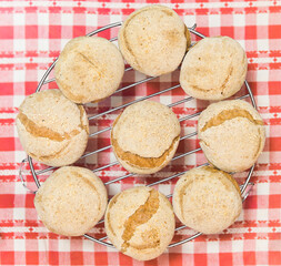 Homemade gluten-free bread buns placed on a metal grill on red and white tablecloth background