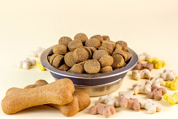 Brown biscuit bones and crunchy organic kibble pieces for dog feed on light background. Healthy dry pet food concept.